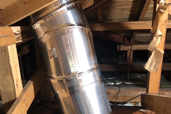 屋根裏に穴をあけてチューブを通す様子